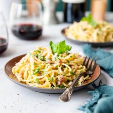 a plate of spaghetti carbonara with a fork