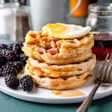 a stack of savory waffles with an over easy egg on top