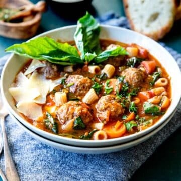 meatball soup recipe in a bowl with basil and parmesan over top