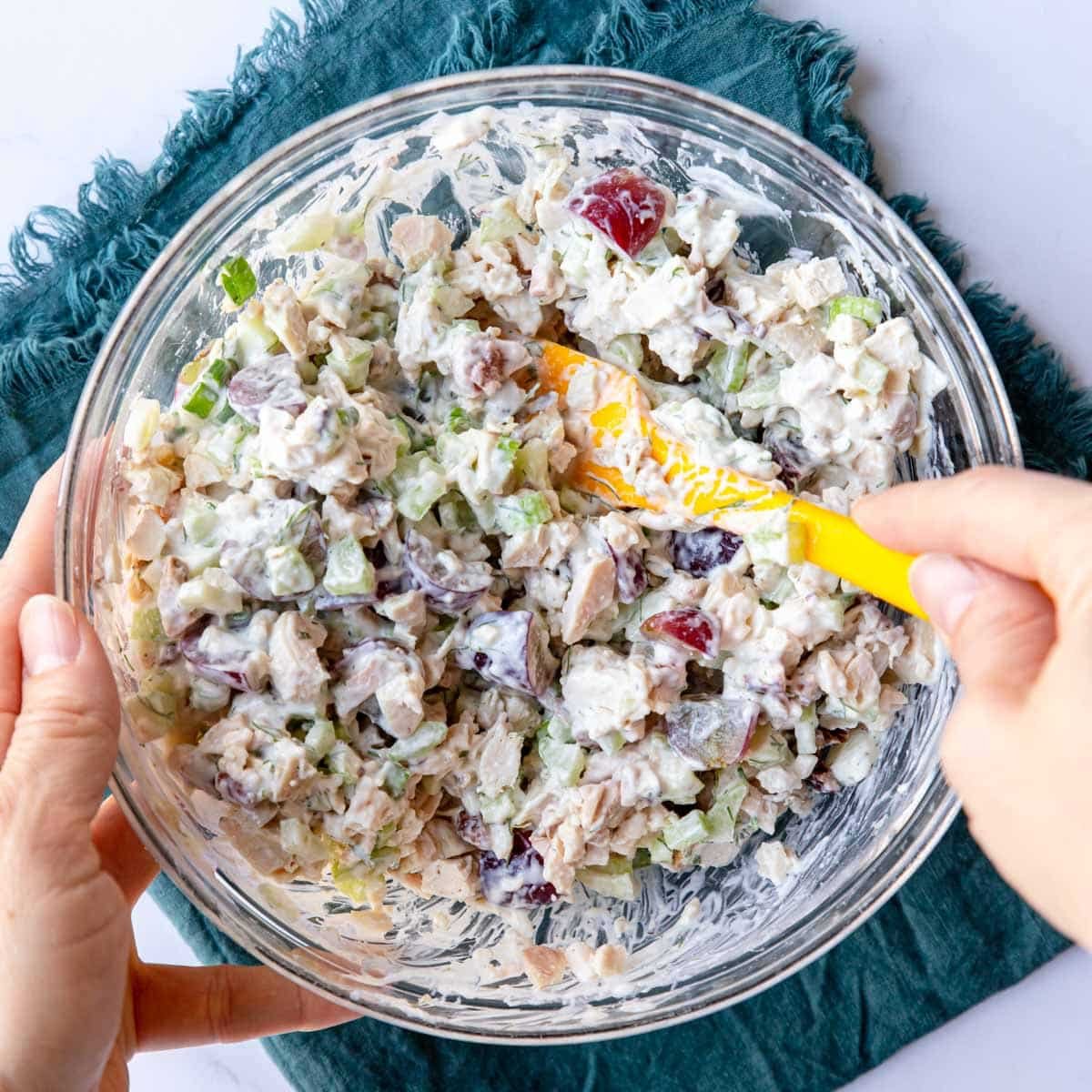mixing chicken salad with grapes in a bowl