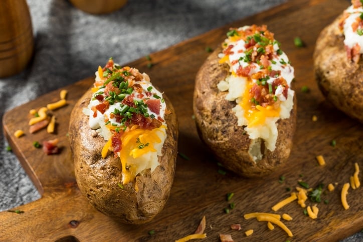 two baked potatoes stuffed with sour cream, cheese and bacon
