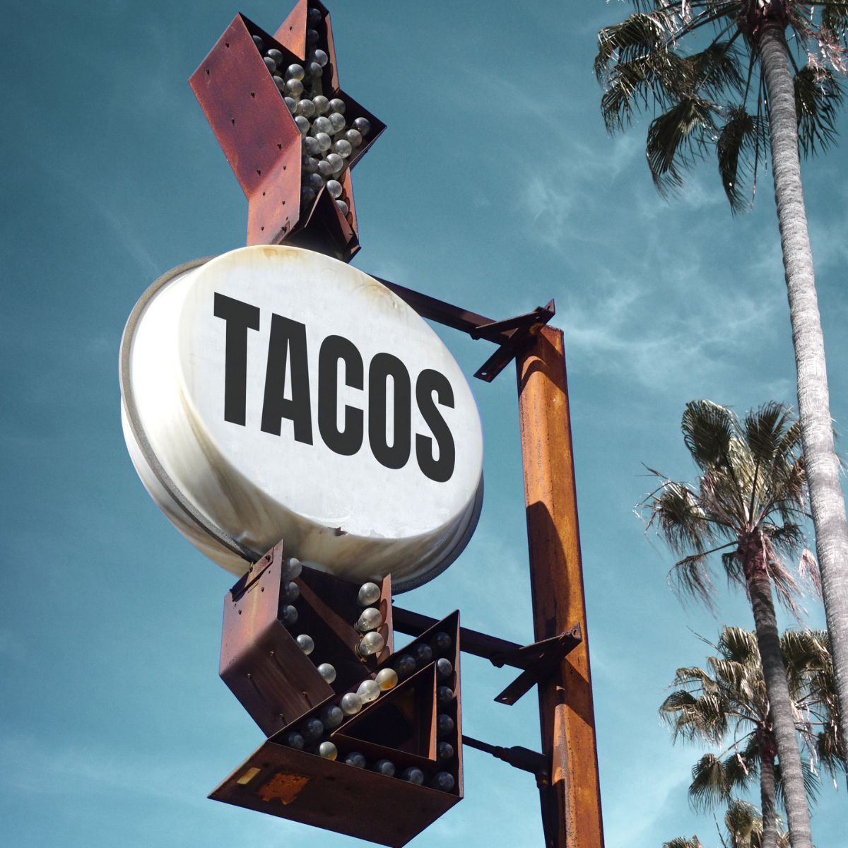 a sign that says tacos and palm trees to the side