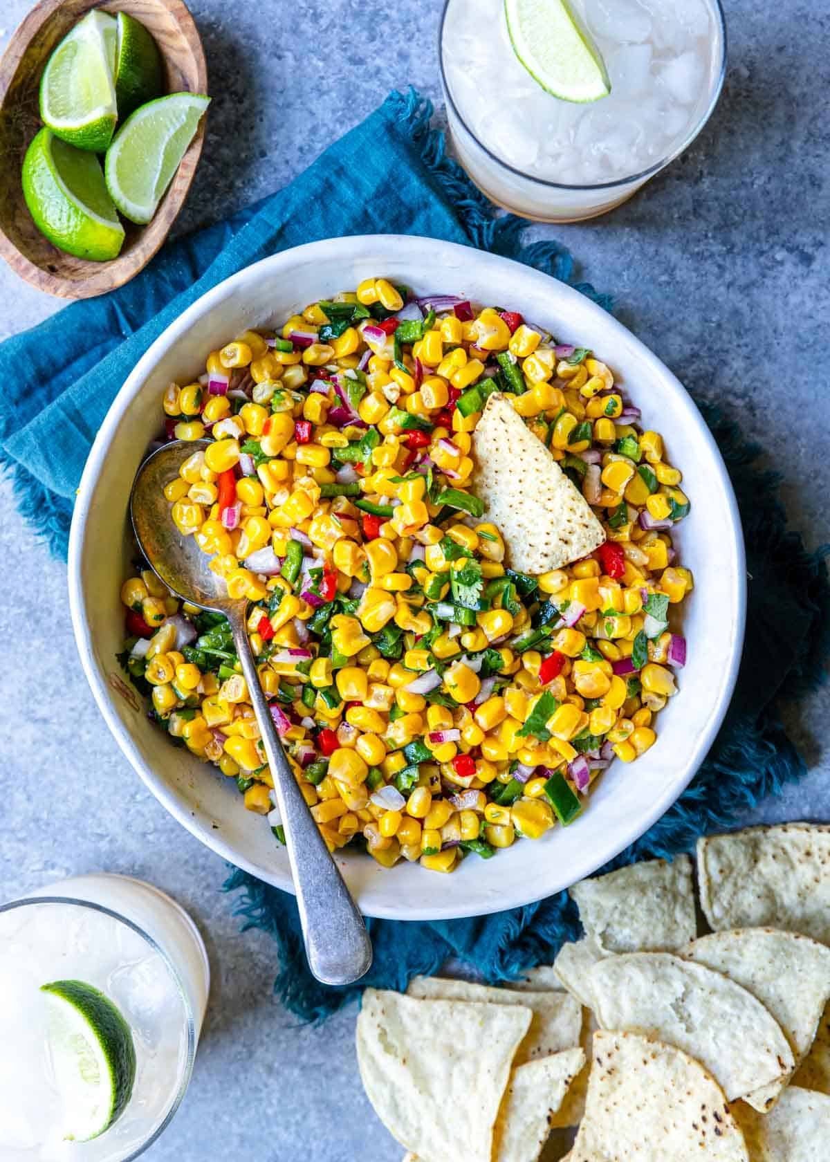 a bowl of corn salsa with a chip and a spoon