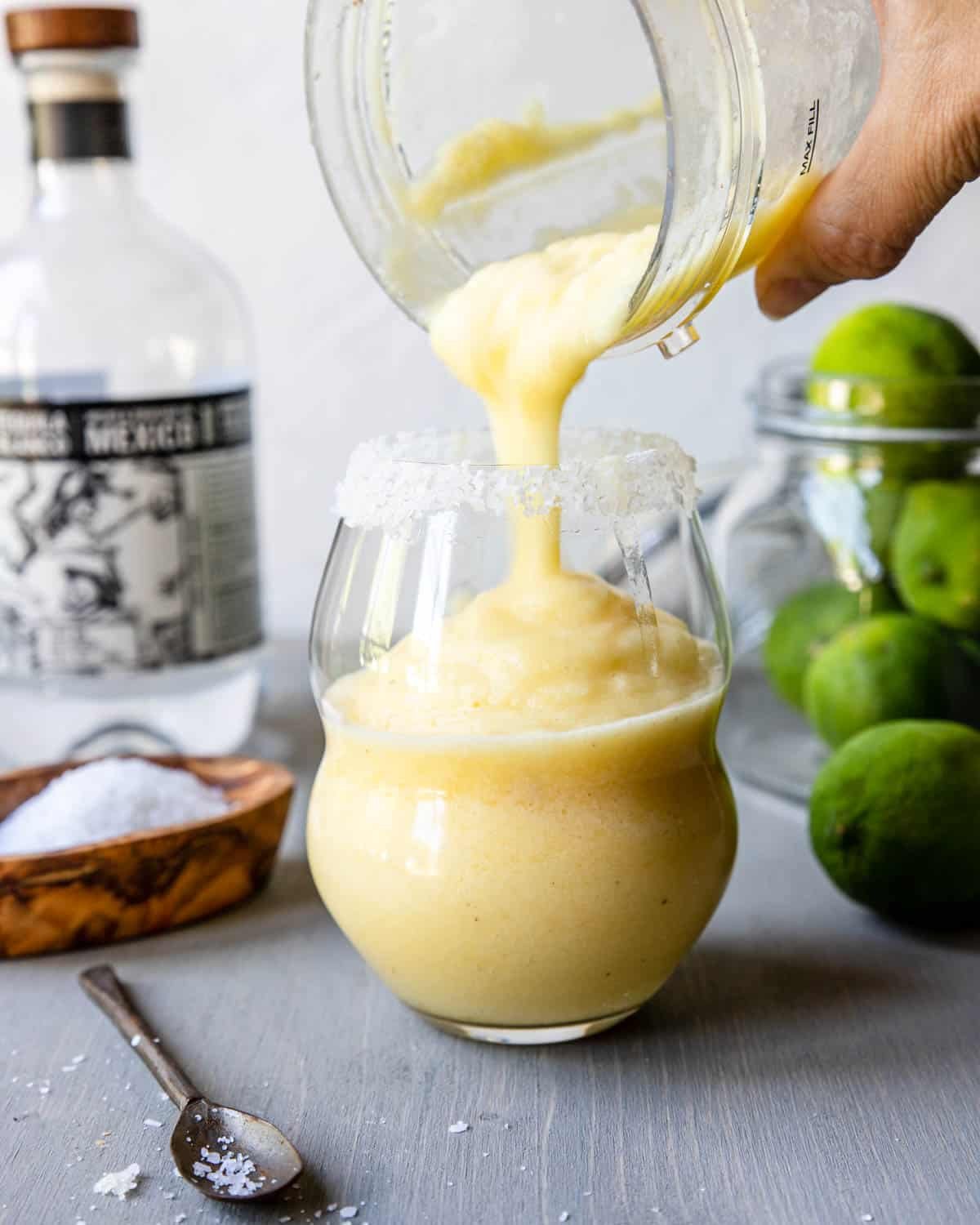 pouring a frozen pineapple margarita from a blender into a glass