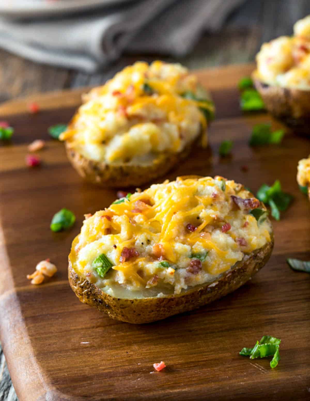 loaded baked potatoes on a cutting board