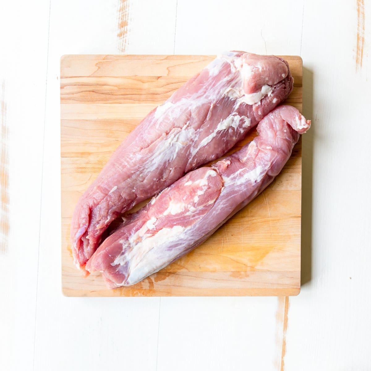 two raw pork tenderloins on a cutting board