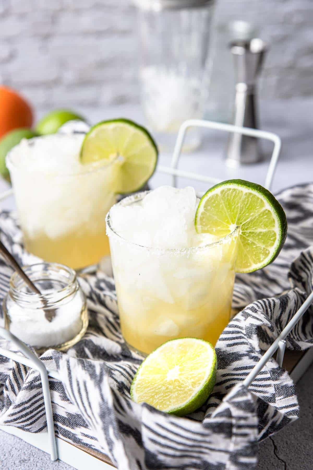 two skinny margaritas on a tray with limes