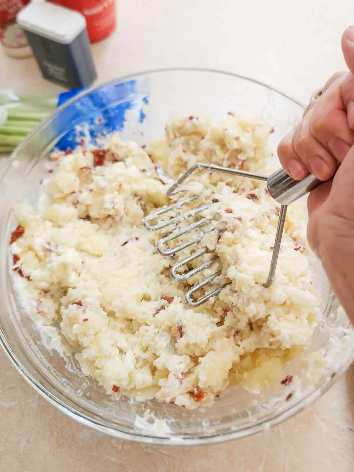 mashing potato mixture with a potato masher