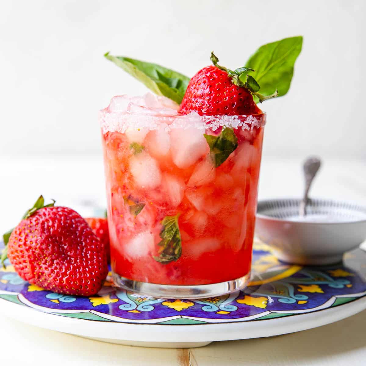 strawberry basil margarita garnished with a salt rim and a fresh strawberry and a sprig of basil