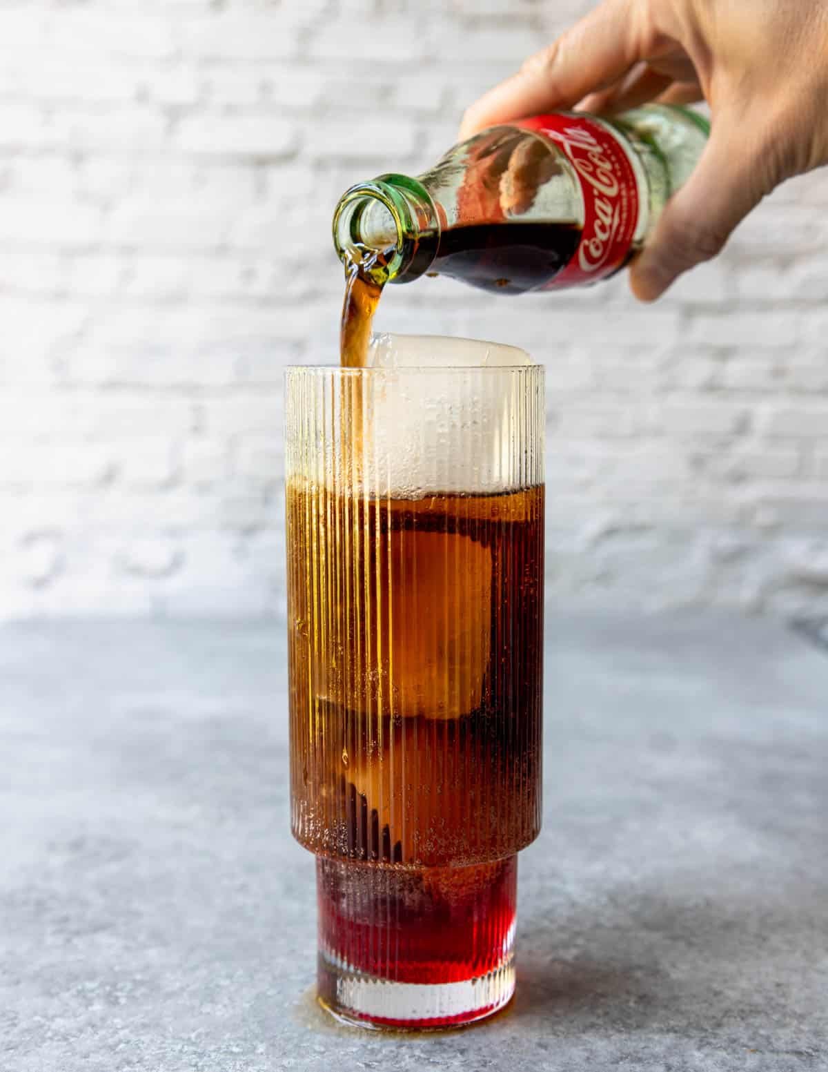 pouring cola over ice and grenadine