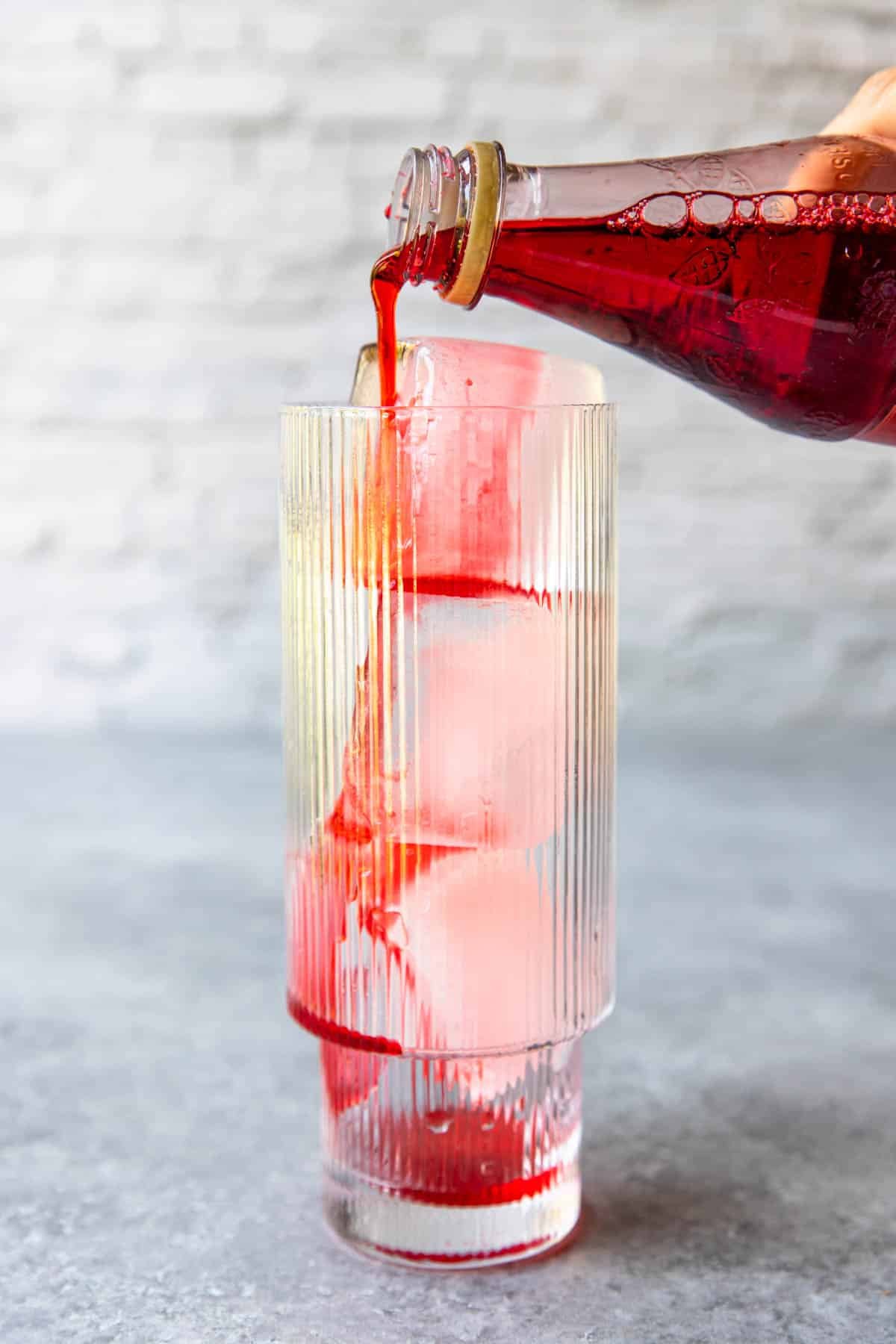 pouring grenadine syrup over ice