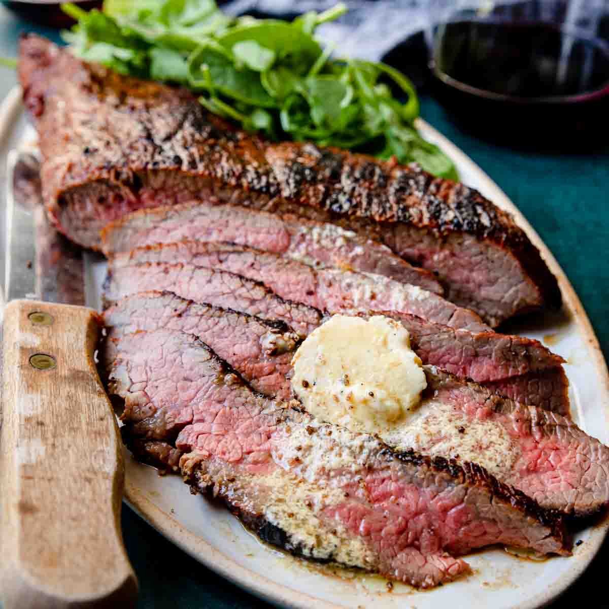 Grilled Tri Tip that is sliced into stirps with butter melting over top
