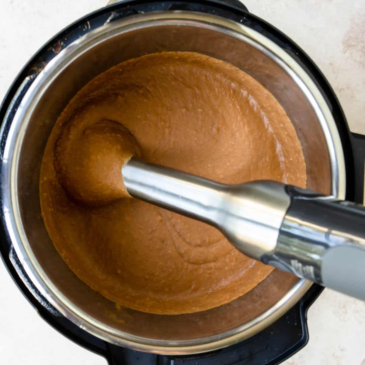 pureed refried beans in the instant pot with an immersion blender