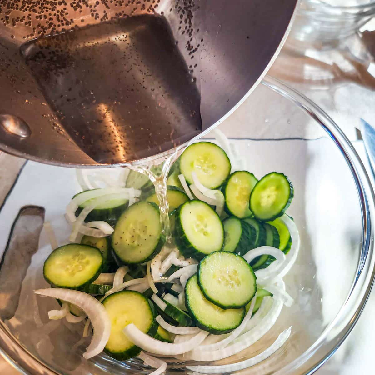 pouring vinegar mixture over cucumbers and onion