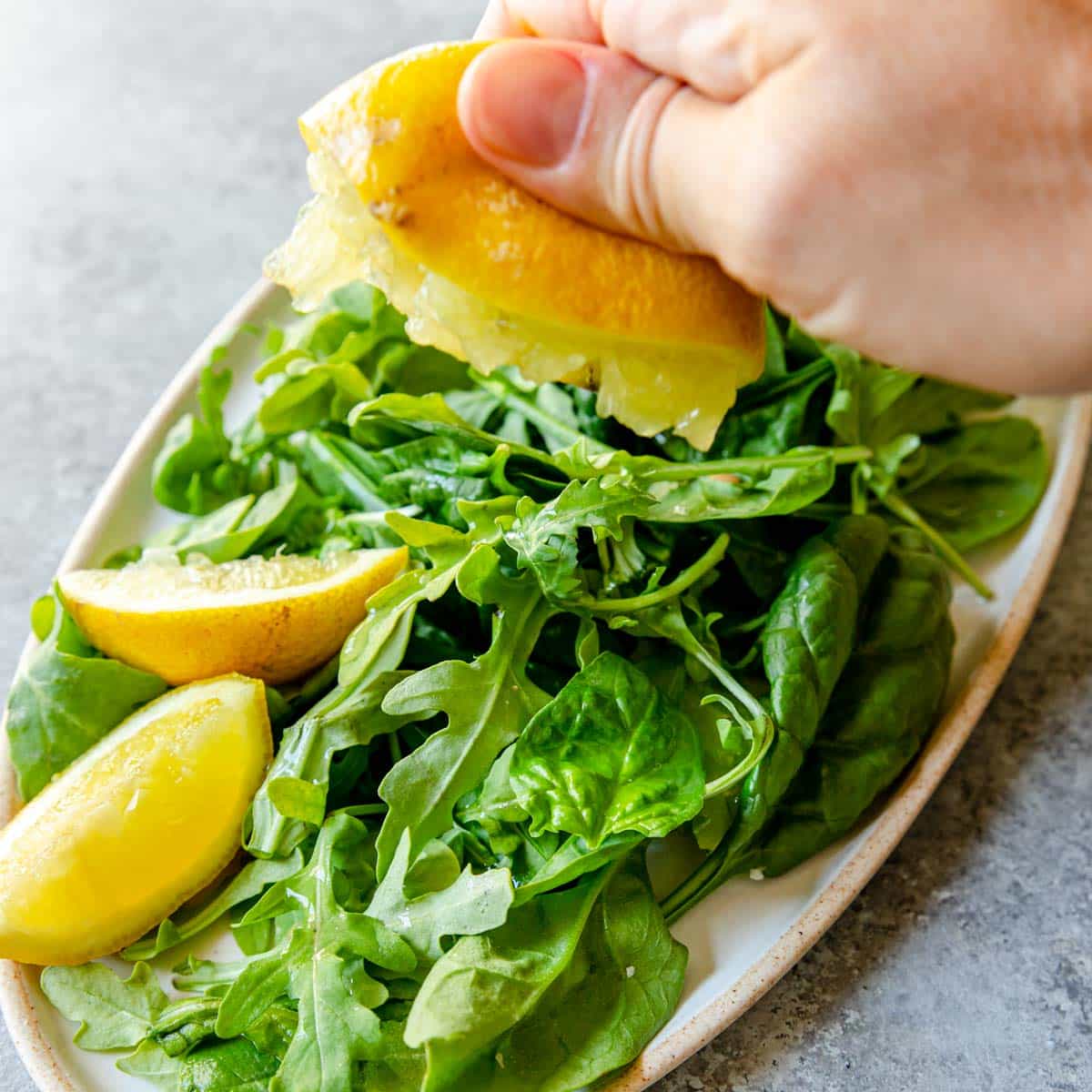 squeezing lemon over greens
