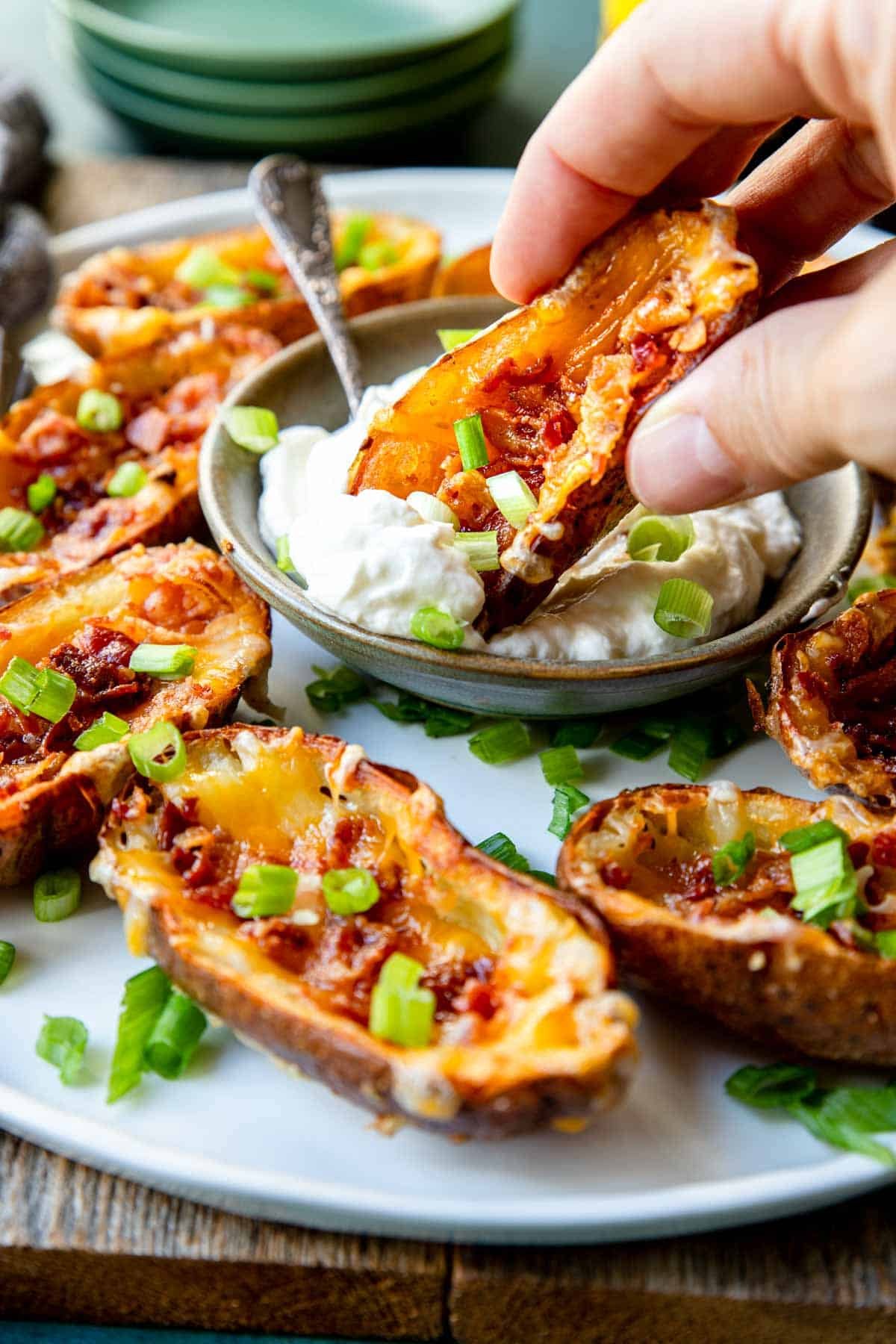 loaded potato skin being dipped in a sour cream dip 
