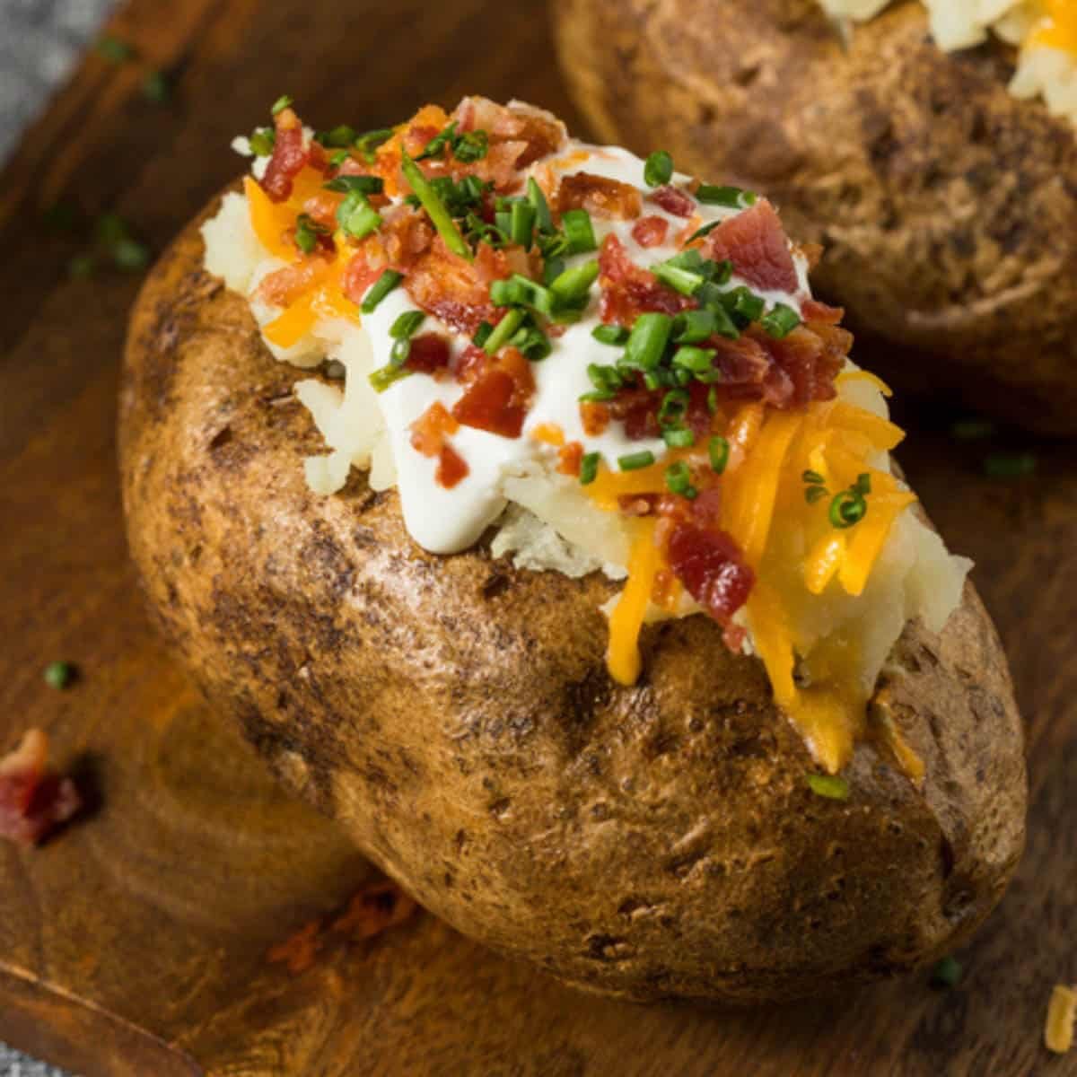 A baked potato filled with sour cream, cheese, bacon and green onions