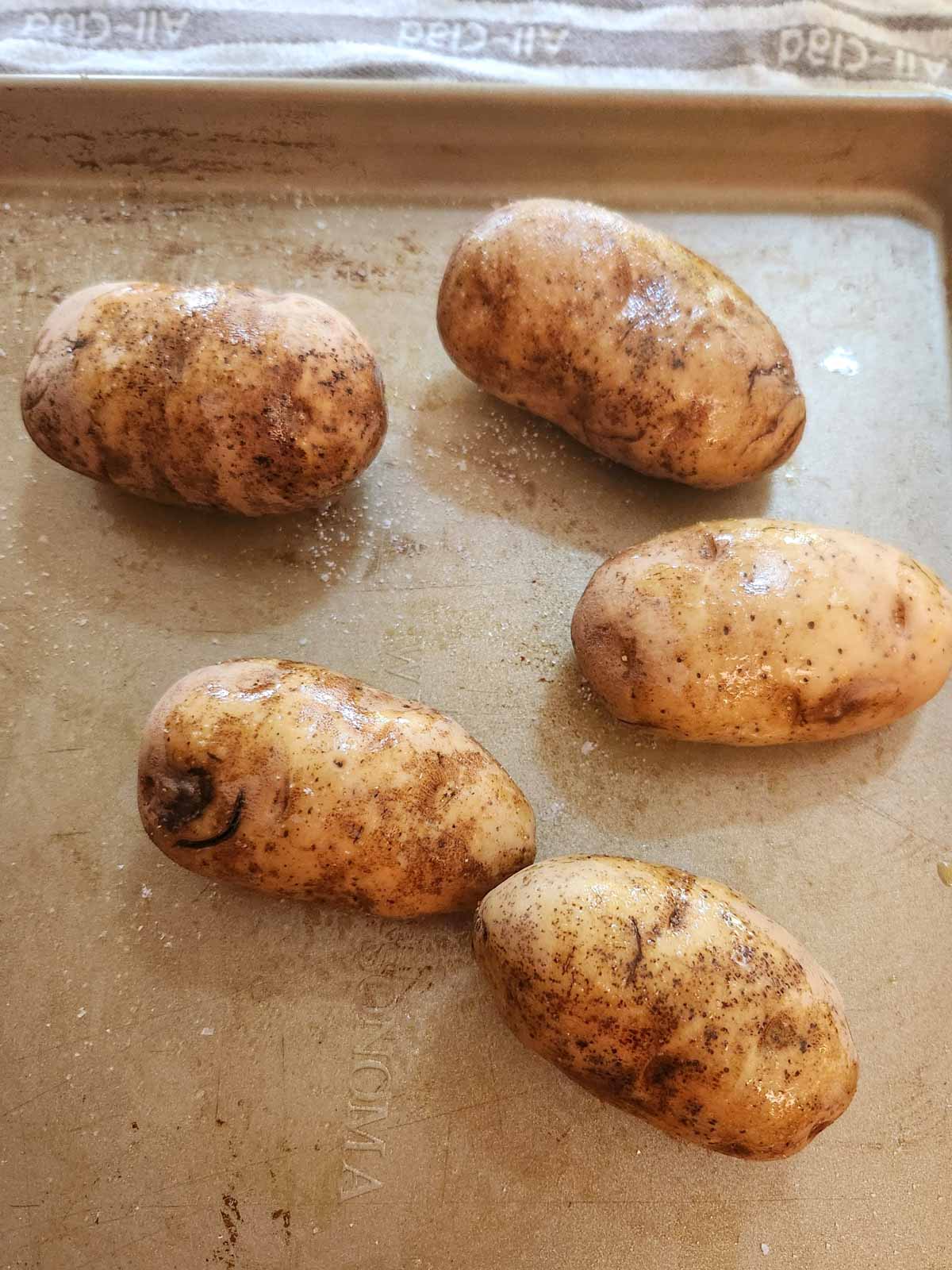 russet potatoes that are pierced with a knife and coated in olive oil and kosher salt