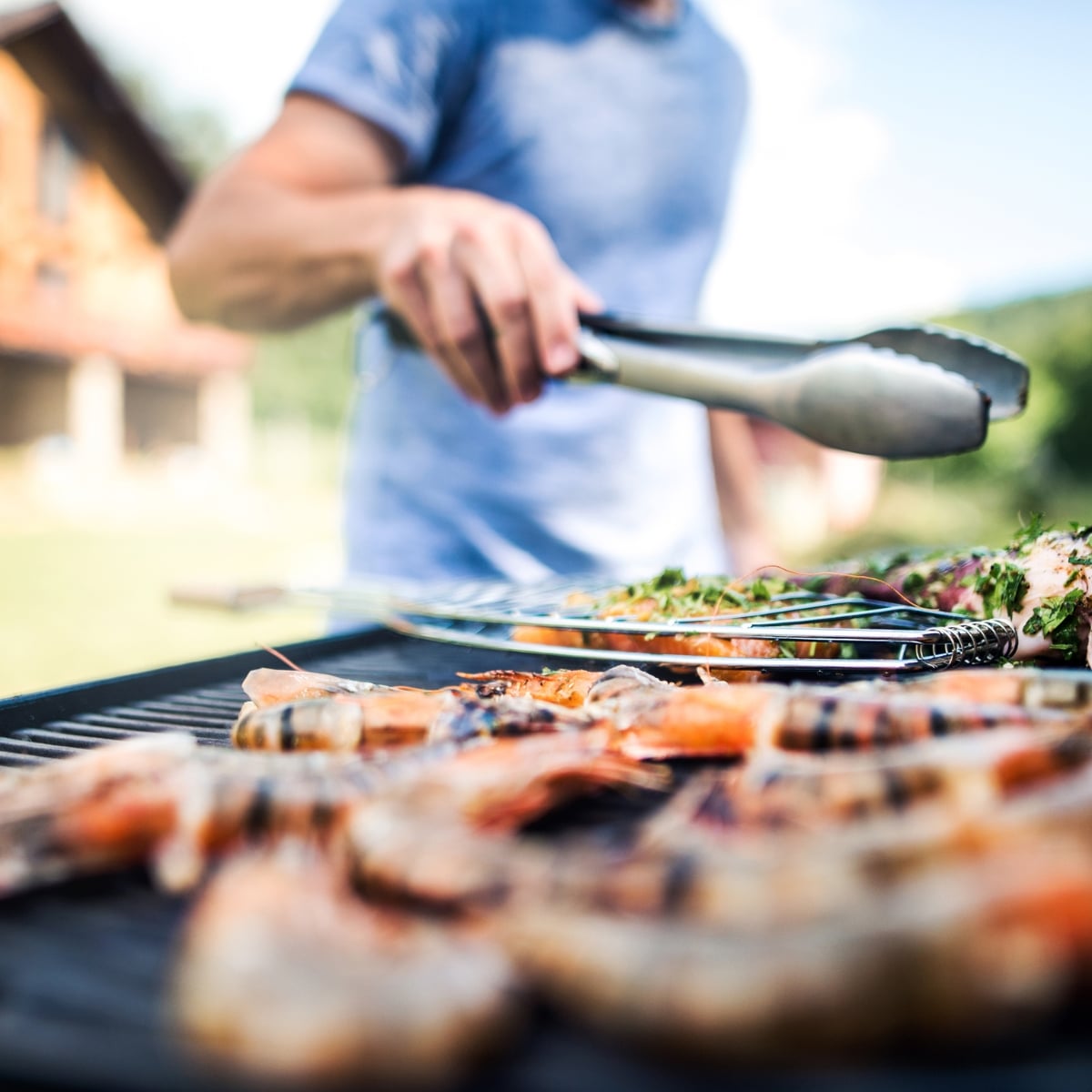 close up of a grill with a man holding tongs