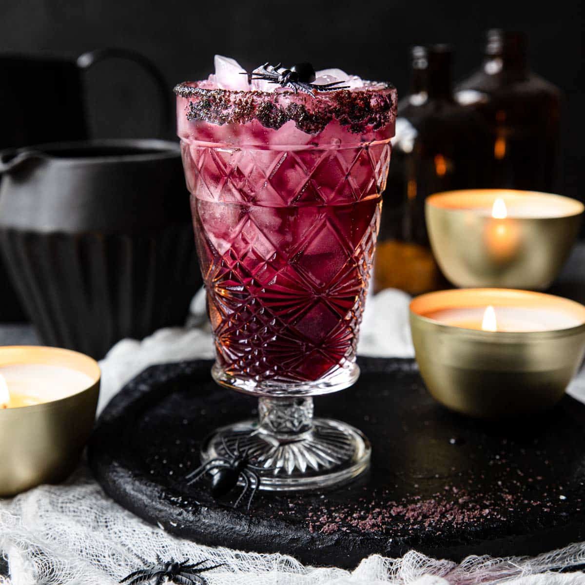Purple margarita with fake spiders around and candles lit