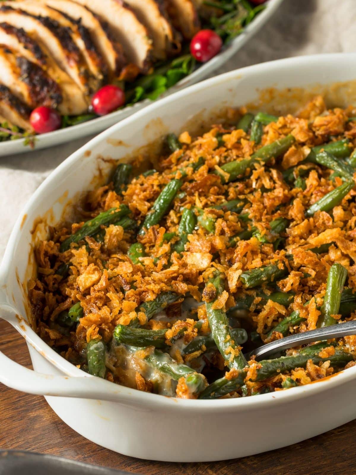 close up picture of green bean casserole with sliced turkey in the background
