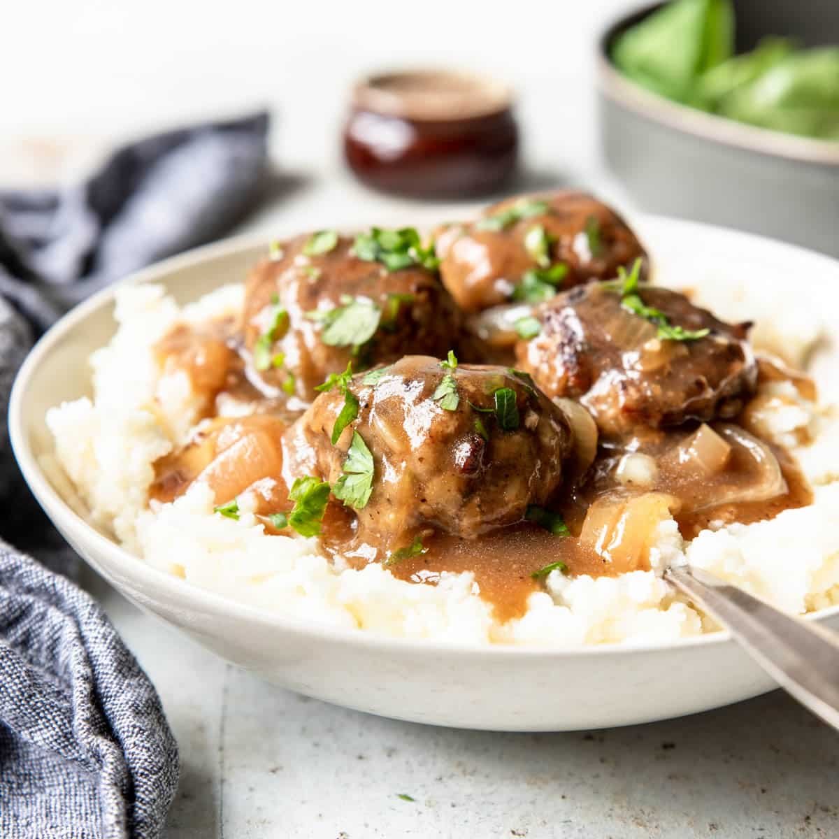 meatballs and gravy served over mashed potatoes and topped with fresh chopped parsley
