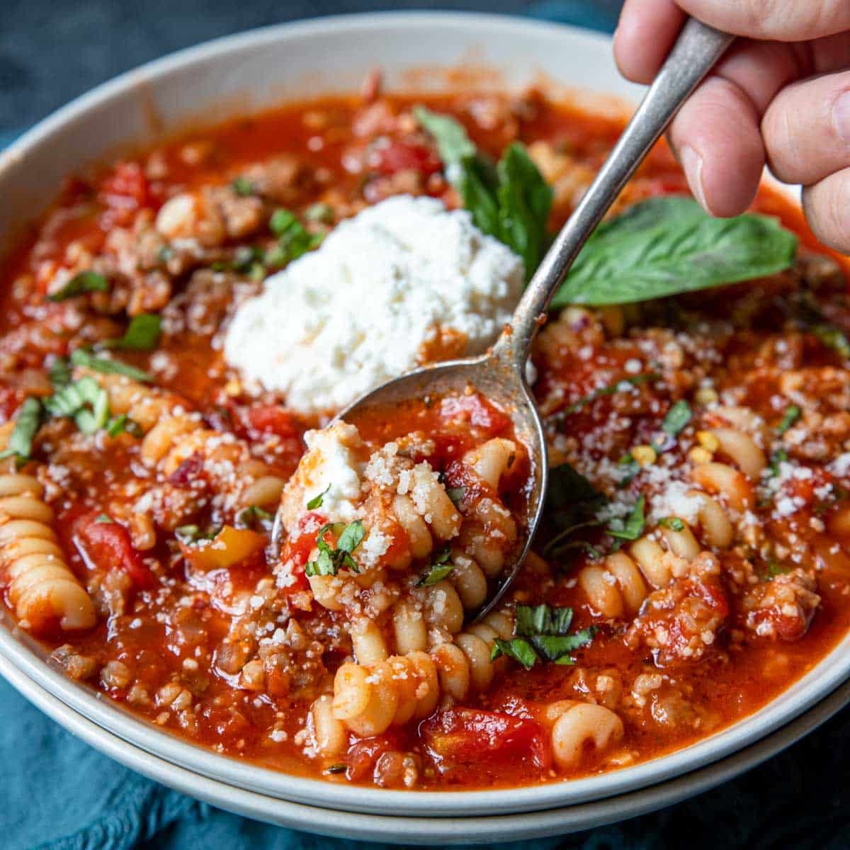a bowl of lasagna soup topped with ricotta cheese