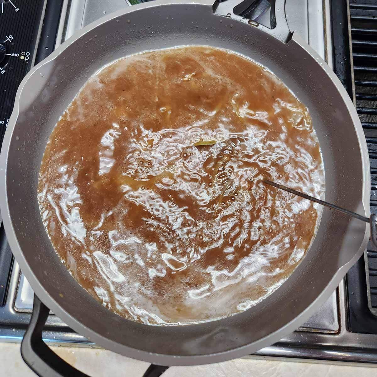 brown gravy liquid simmering on the stove top