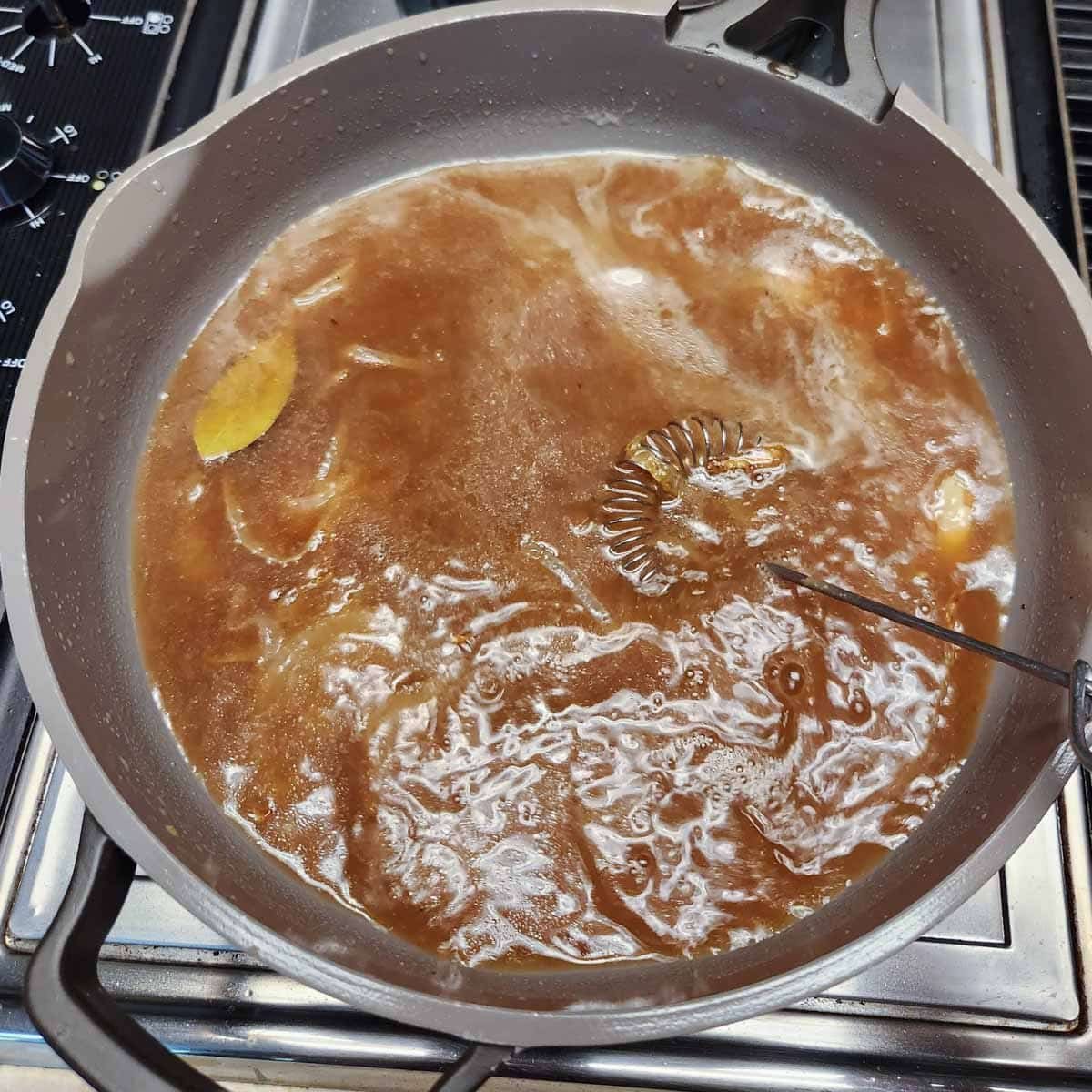 brown gravy being whisked in a skillet