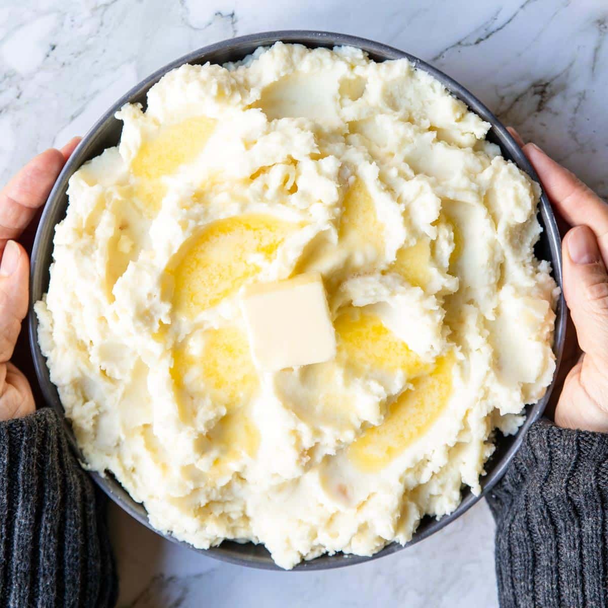 a large bowl of roasted garlic mashed potatoes topped with butter