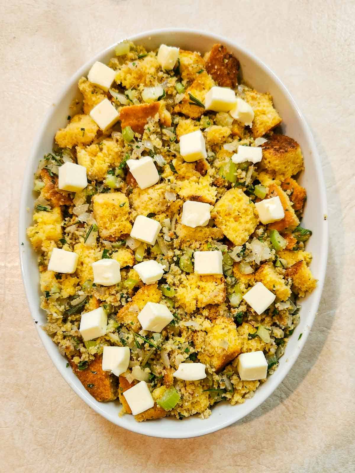 cornbread stuffing in a casserole dish, topped with cubes of butter