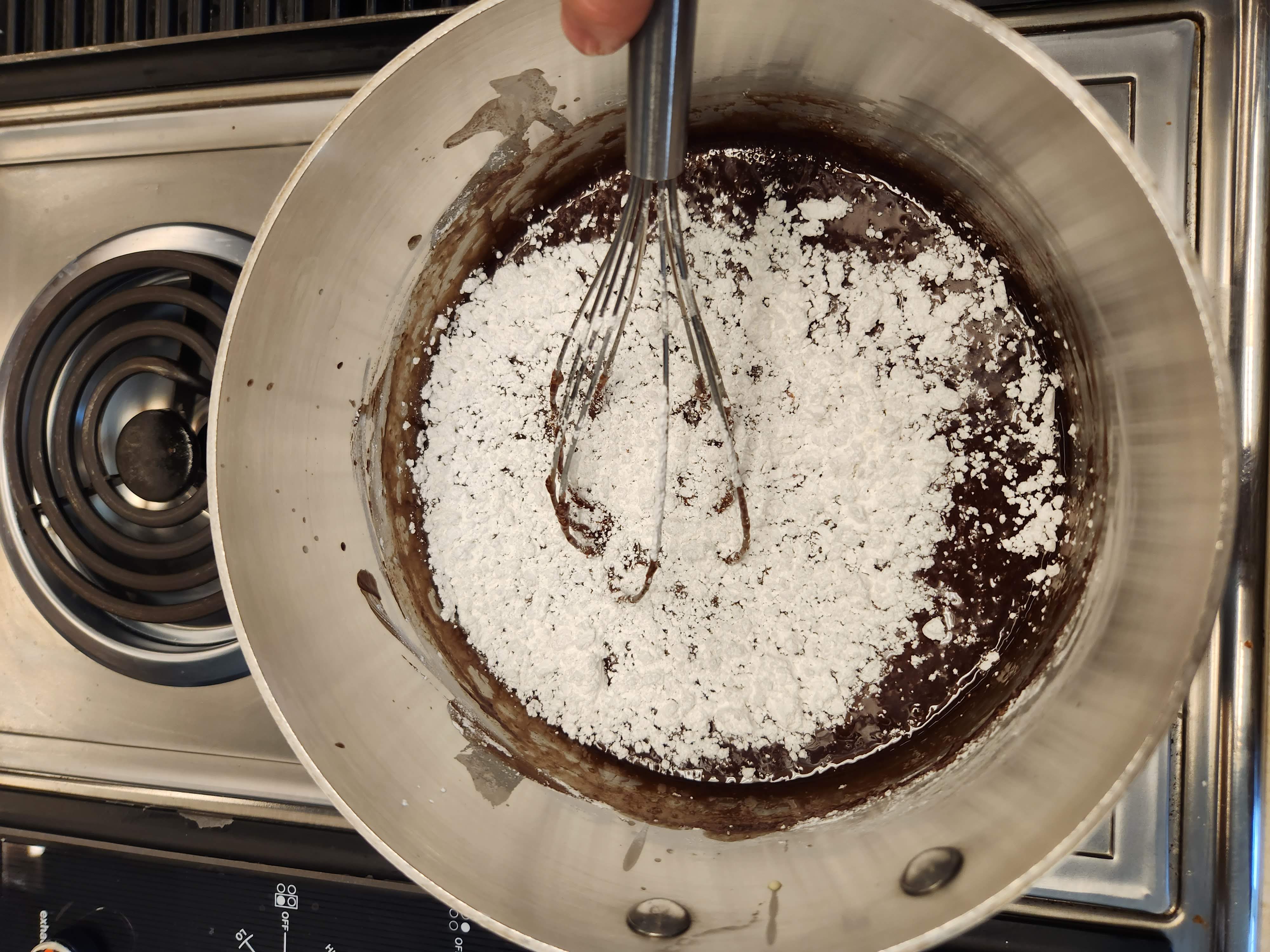 powdered sugar being stirred into a chocolate mixture