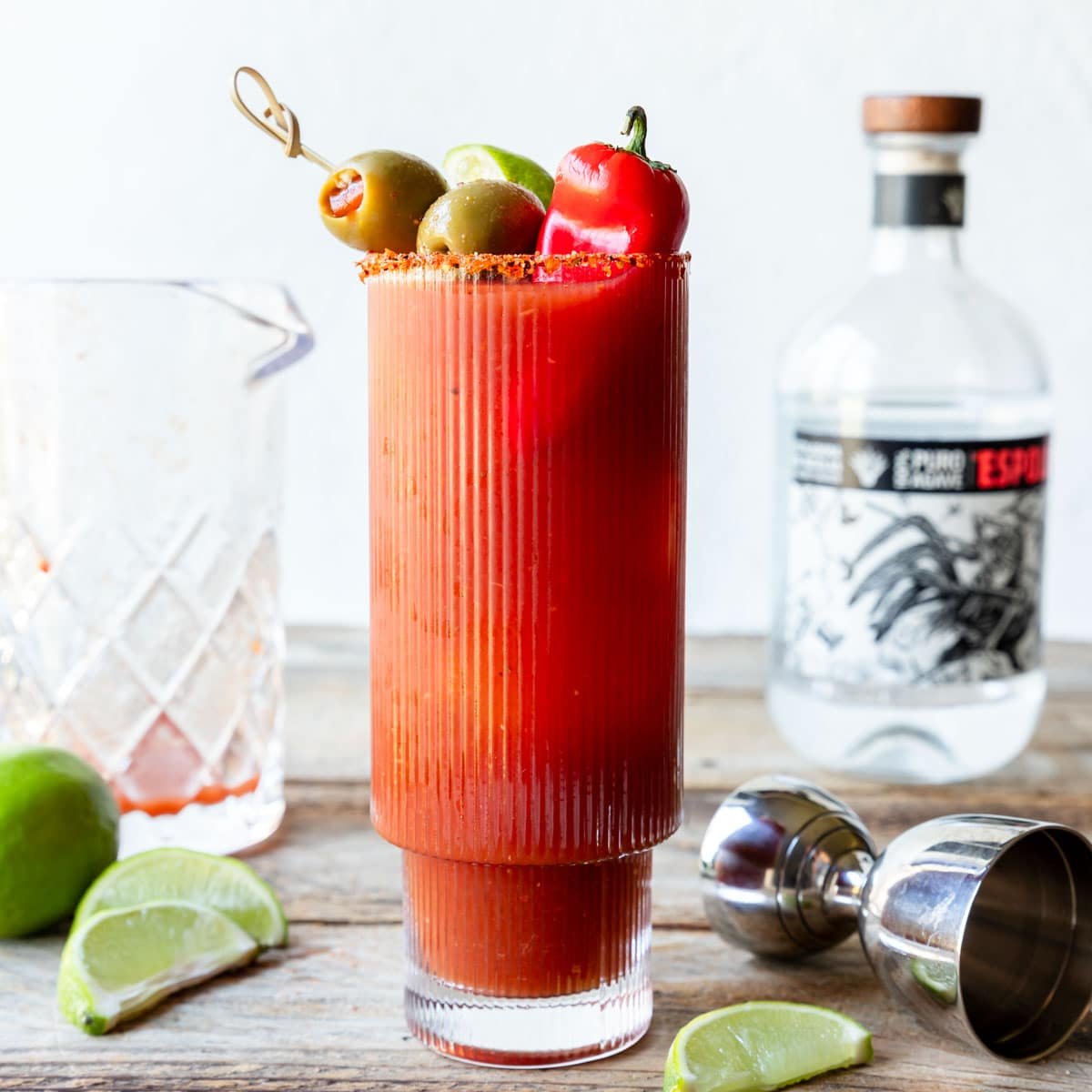 Bloody Maria in a tall glass garnished with peppers and olives