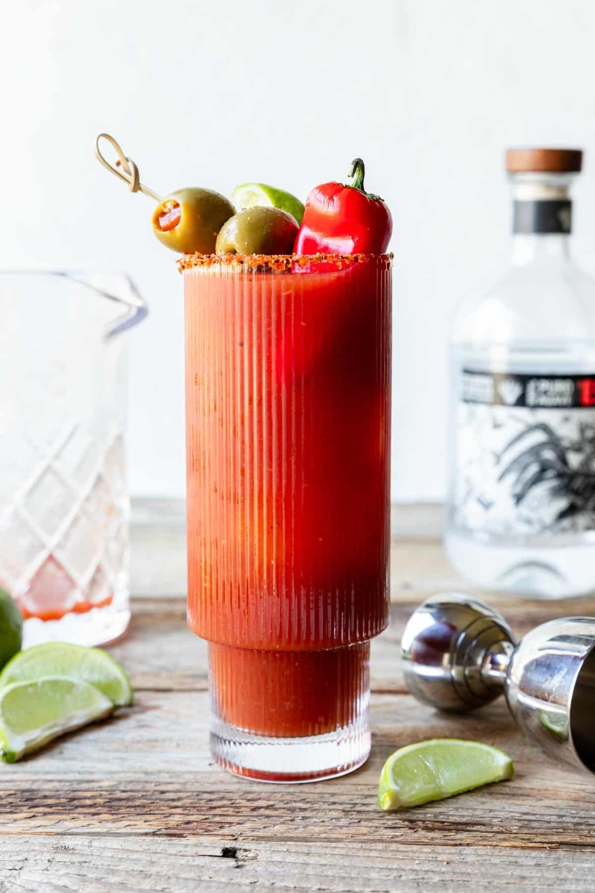 Bloody Maria in a glass garnished with peppers, olives and limes 