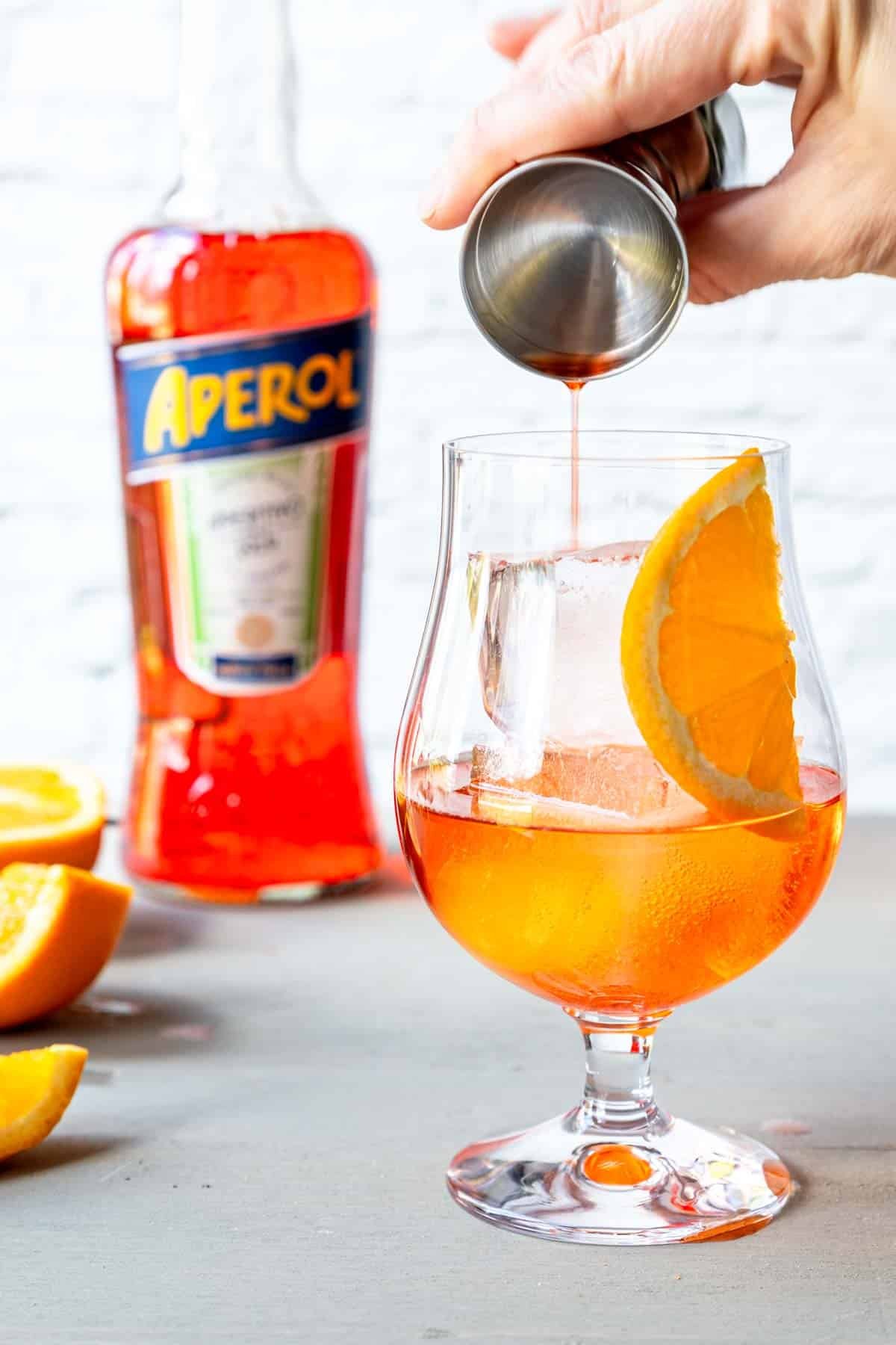 pouring aperol in a stemmed glass