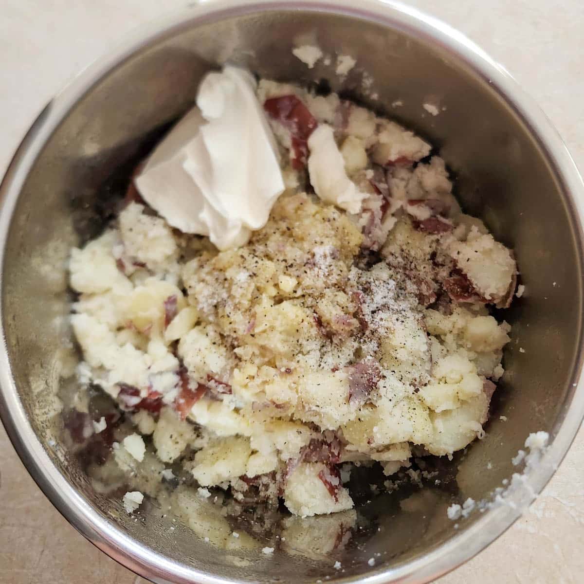boiled red skin potatoes with sour cream, half and half, butter, shallots and garlic in a bowl