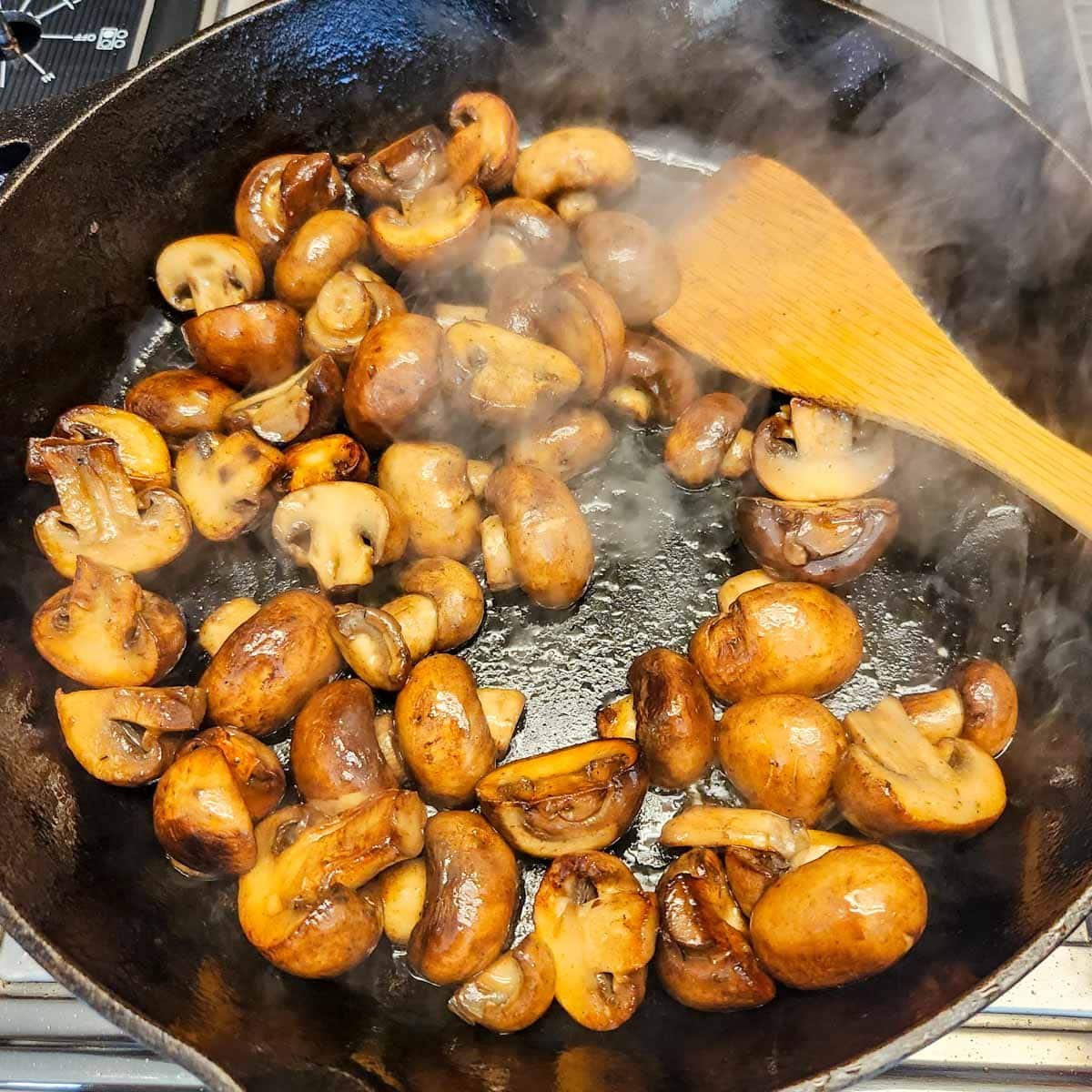mushrooms sauteing in a cast iron skillet