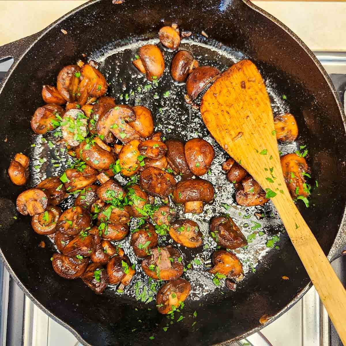 Steak House Mushrooms garnished with parsley in a skillet 