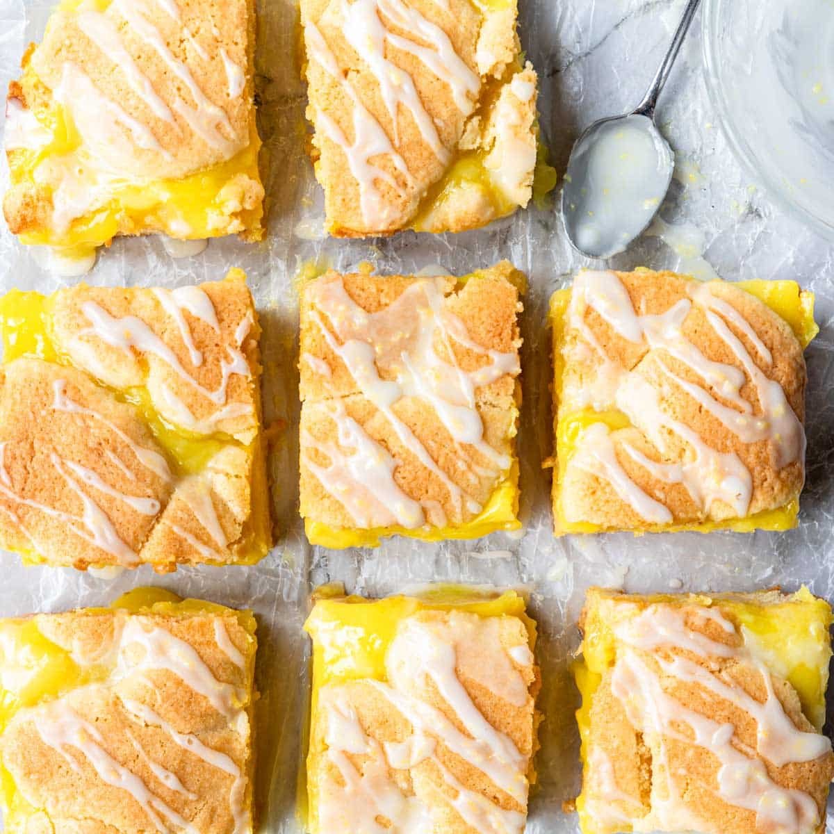 overhead view of lemon pie bars cut into squares and drizzled with lemon glaze