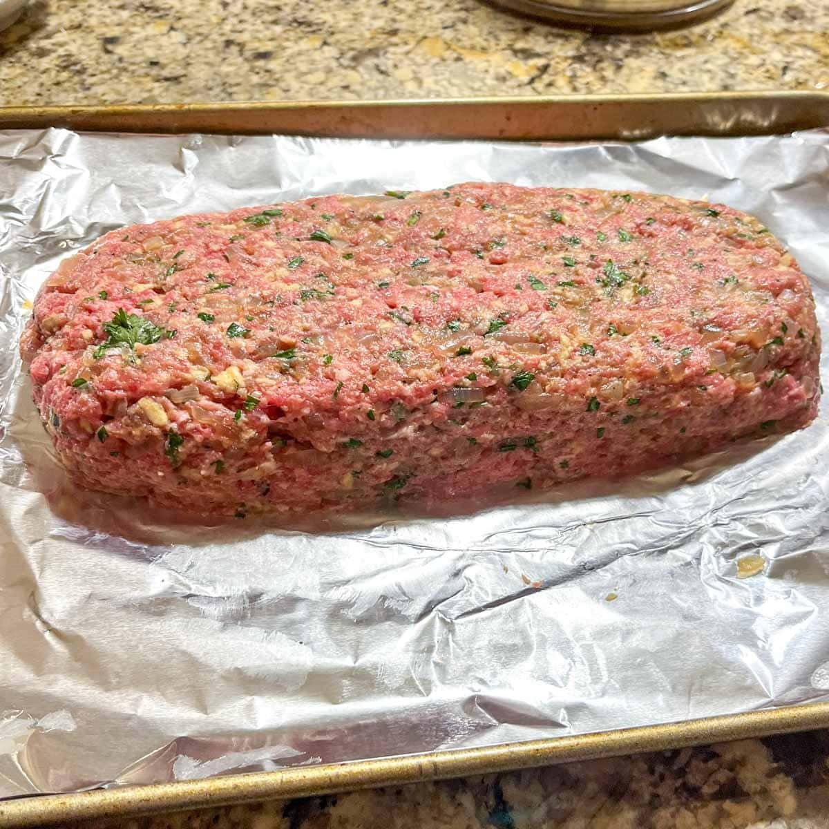 raw meatloaf formed on a foil lined pan.