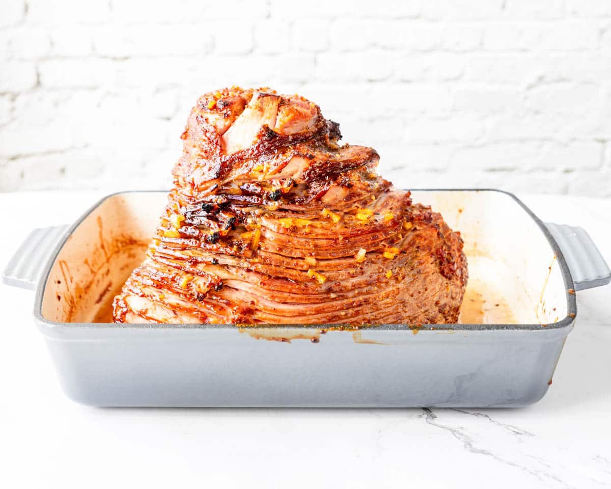 a marmalade glazed ham in a grey baking pan
