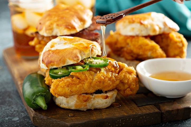 Fried chicken sandwich with hot honey being drizzled over top