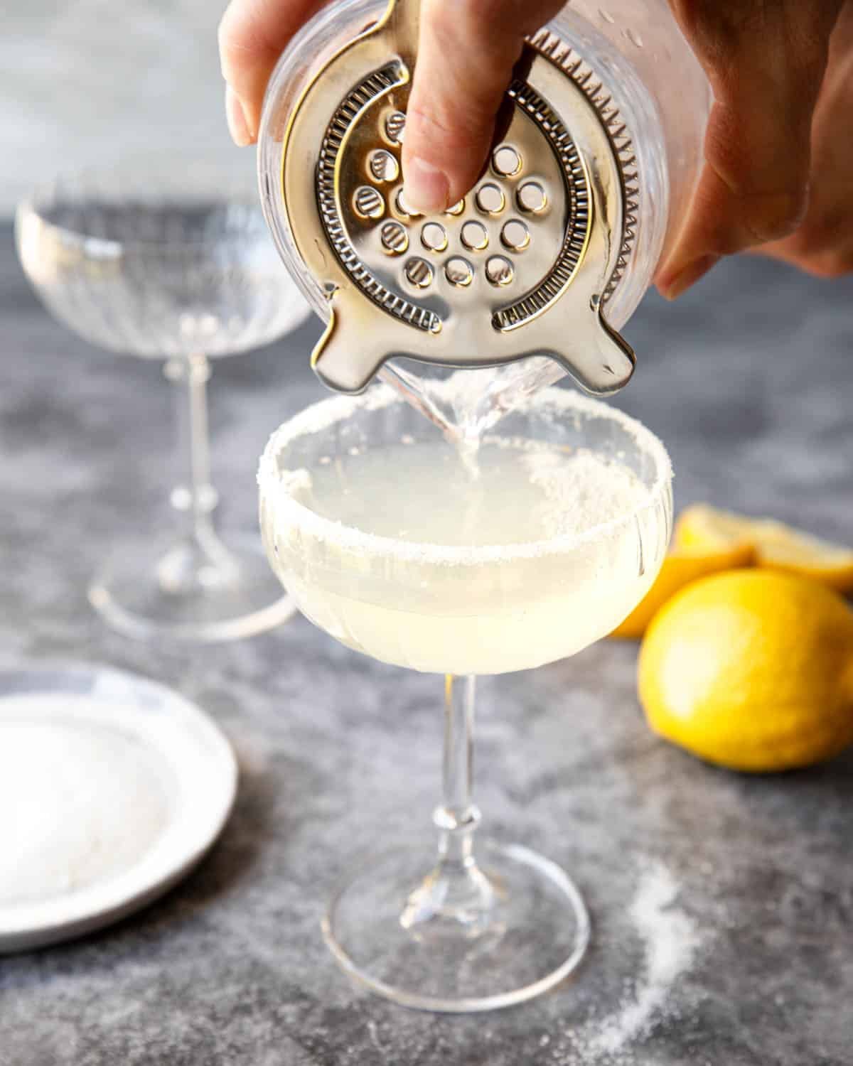 pouring a tequila lemon drop into a coupe glass 