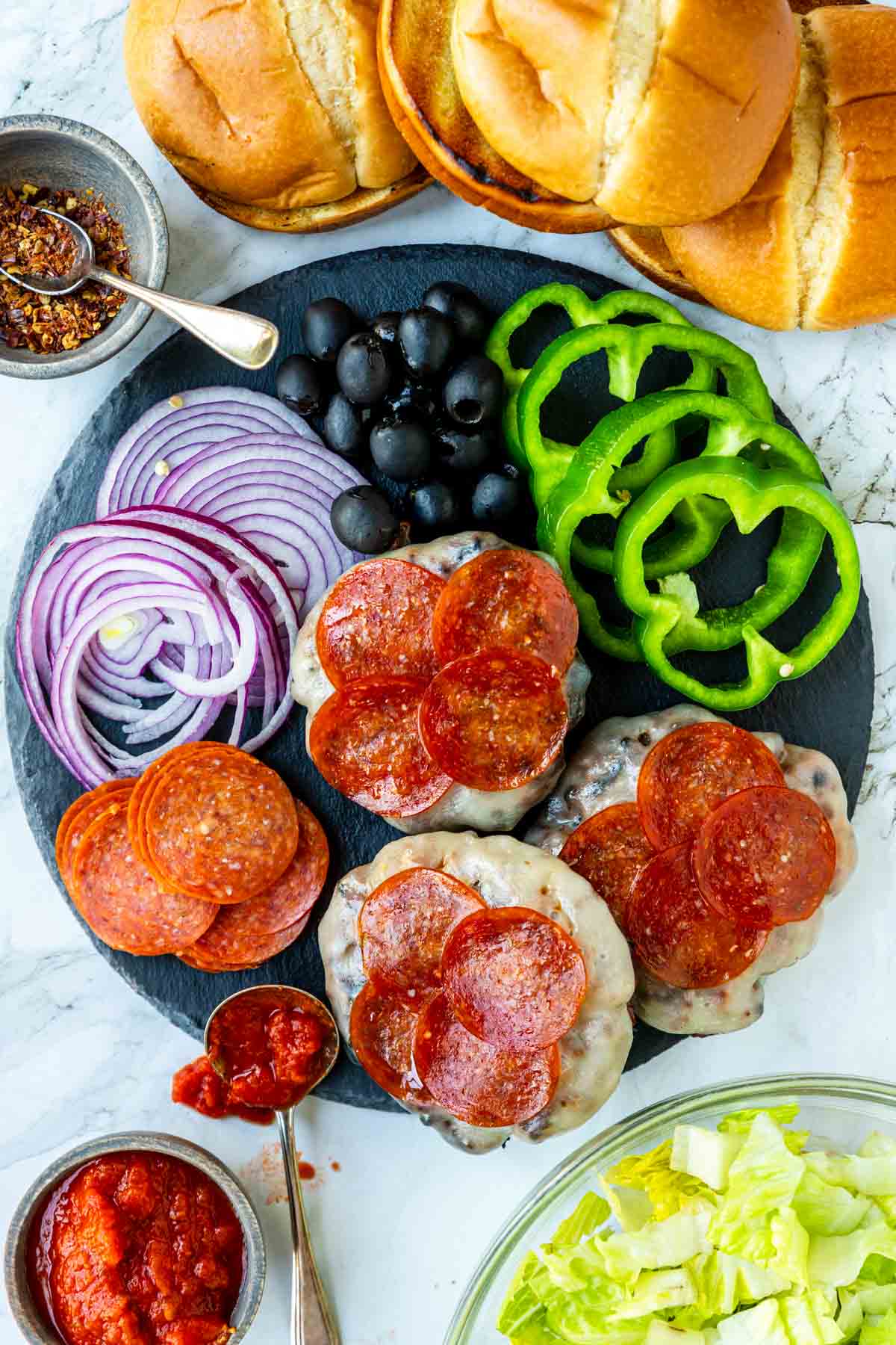 pizza burgers topped with cheese and pepperoni with pizza burger toppings and buns around the platter 