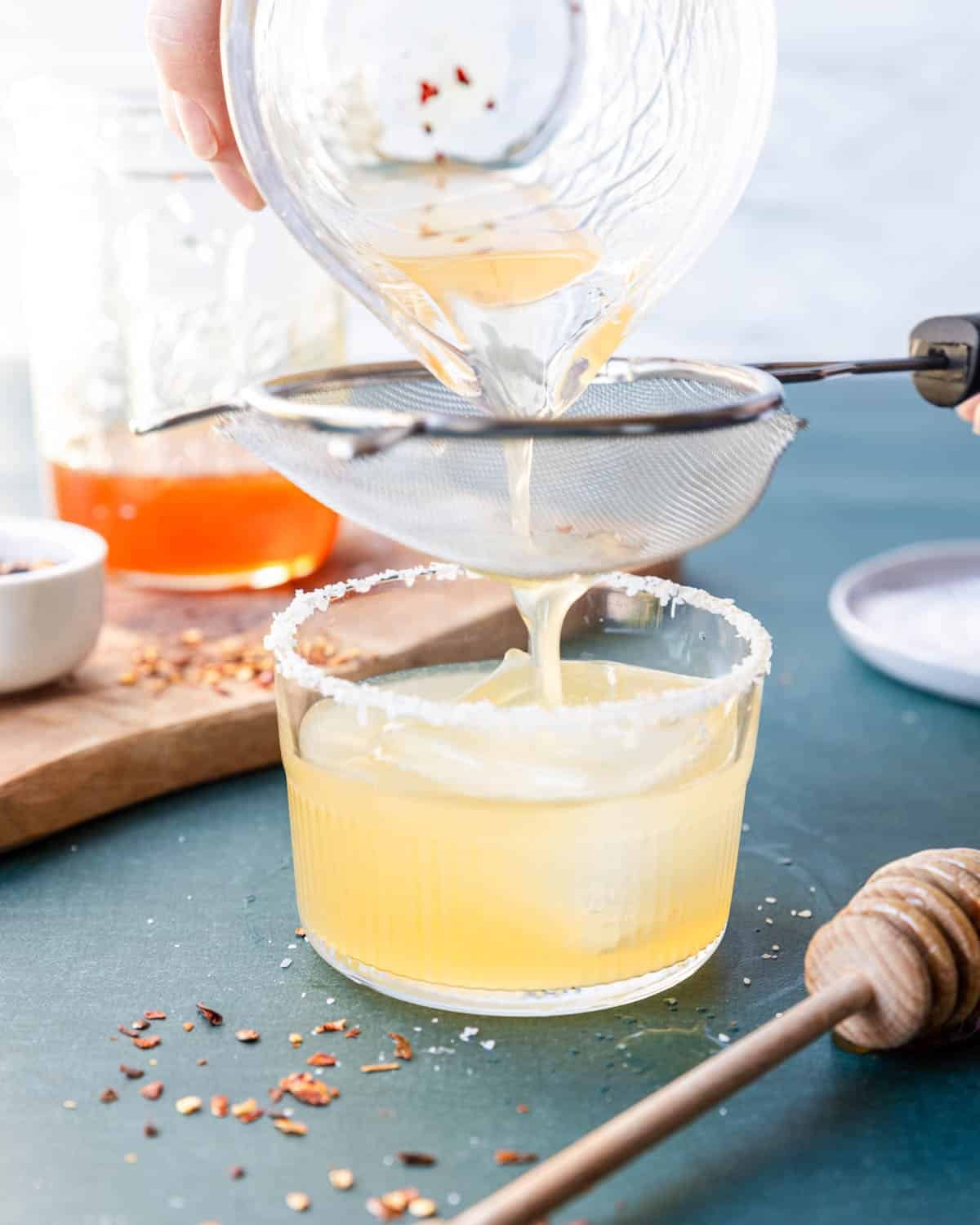 staining a hot honey margarita through a fine mesh strainer 