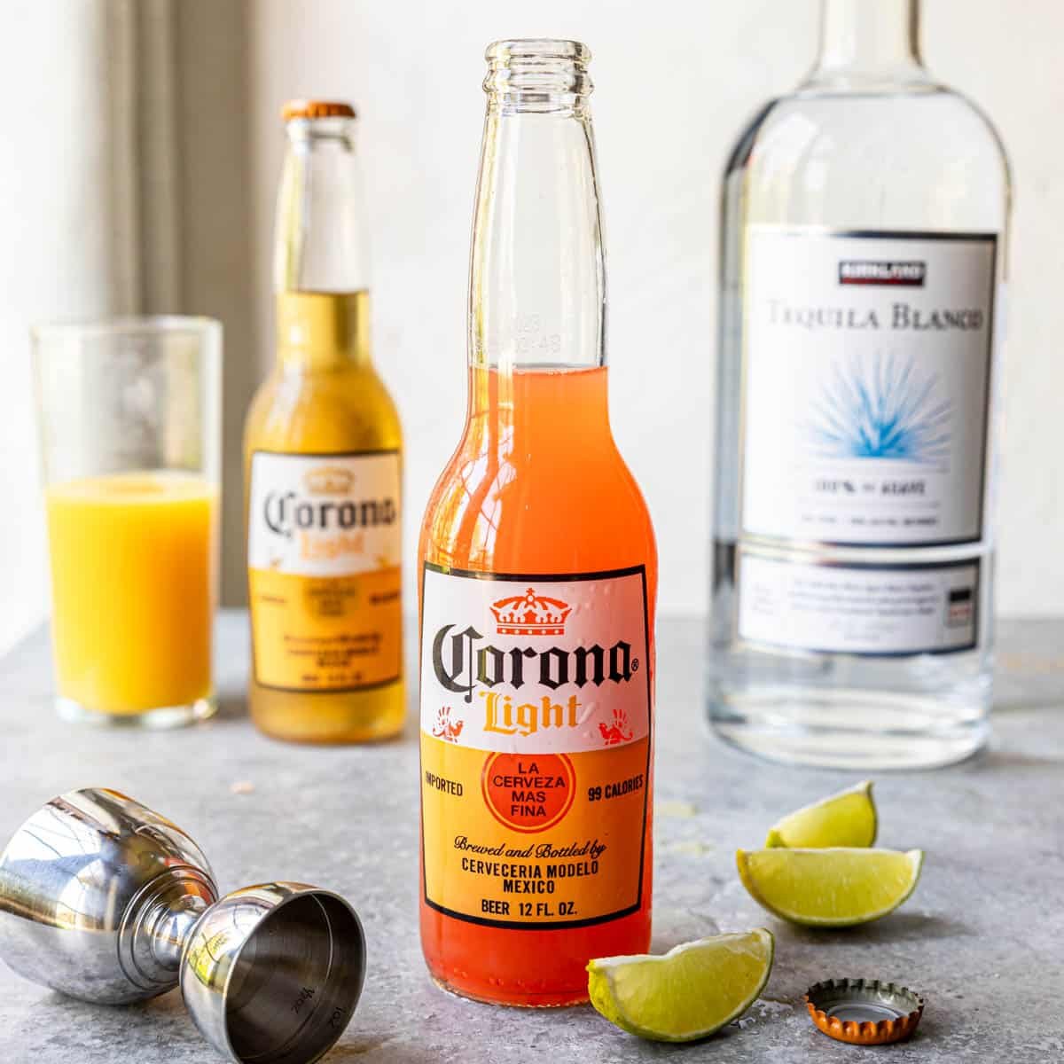 Corona Sunrise in a Corona Light bottle on a table with limes to the side