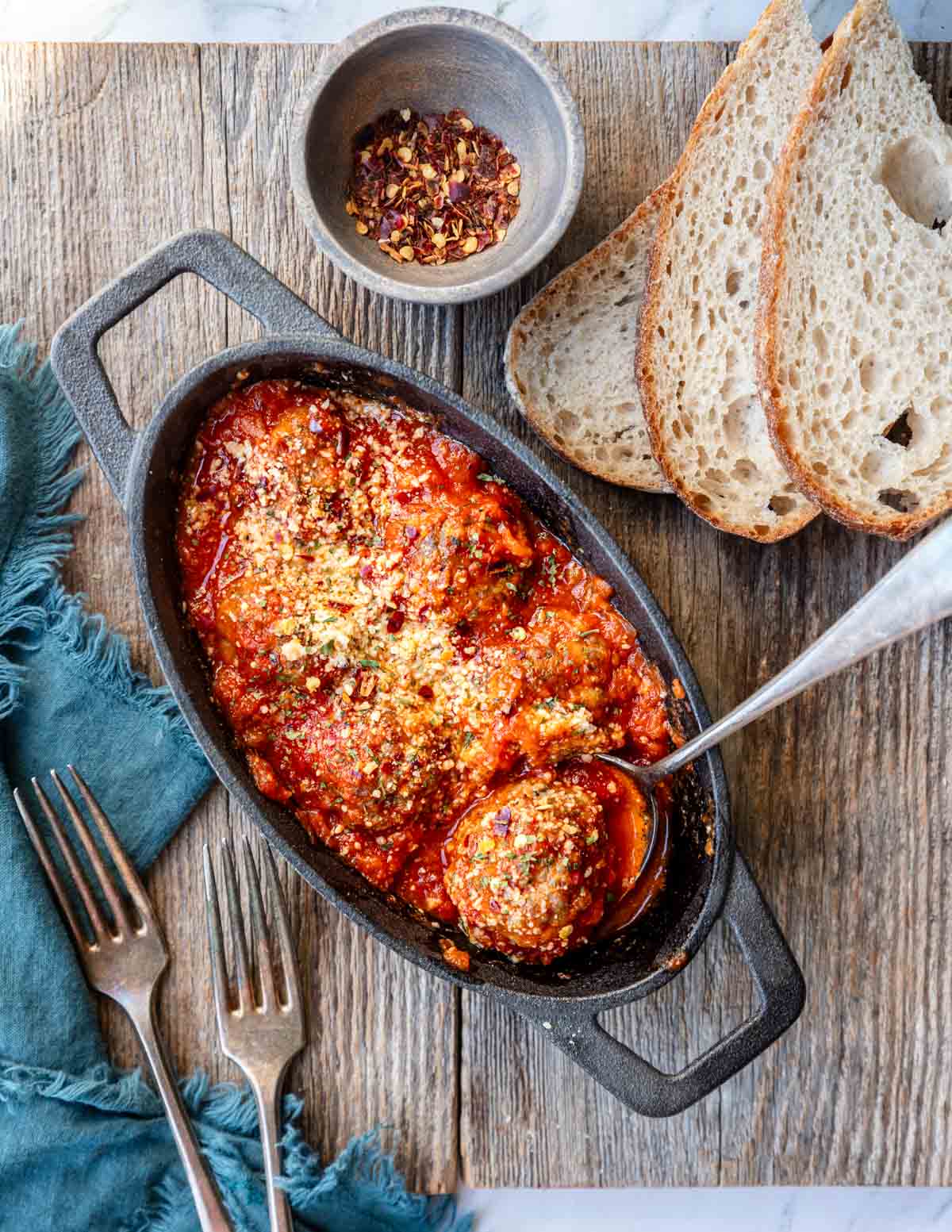 a cast iron pan with Italian Sausage Meatballs with marinara parmesan cheese on top