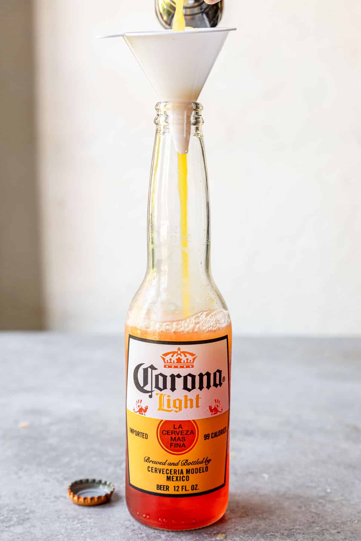 measuring orange juice into a bottle of corona