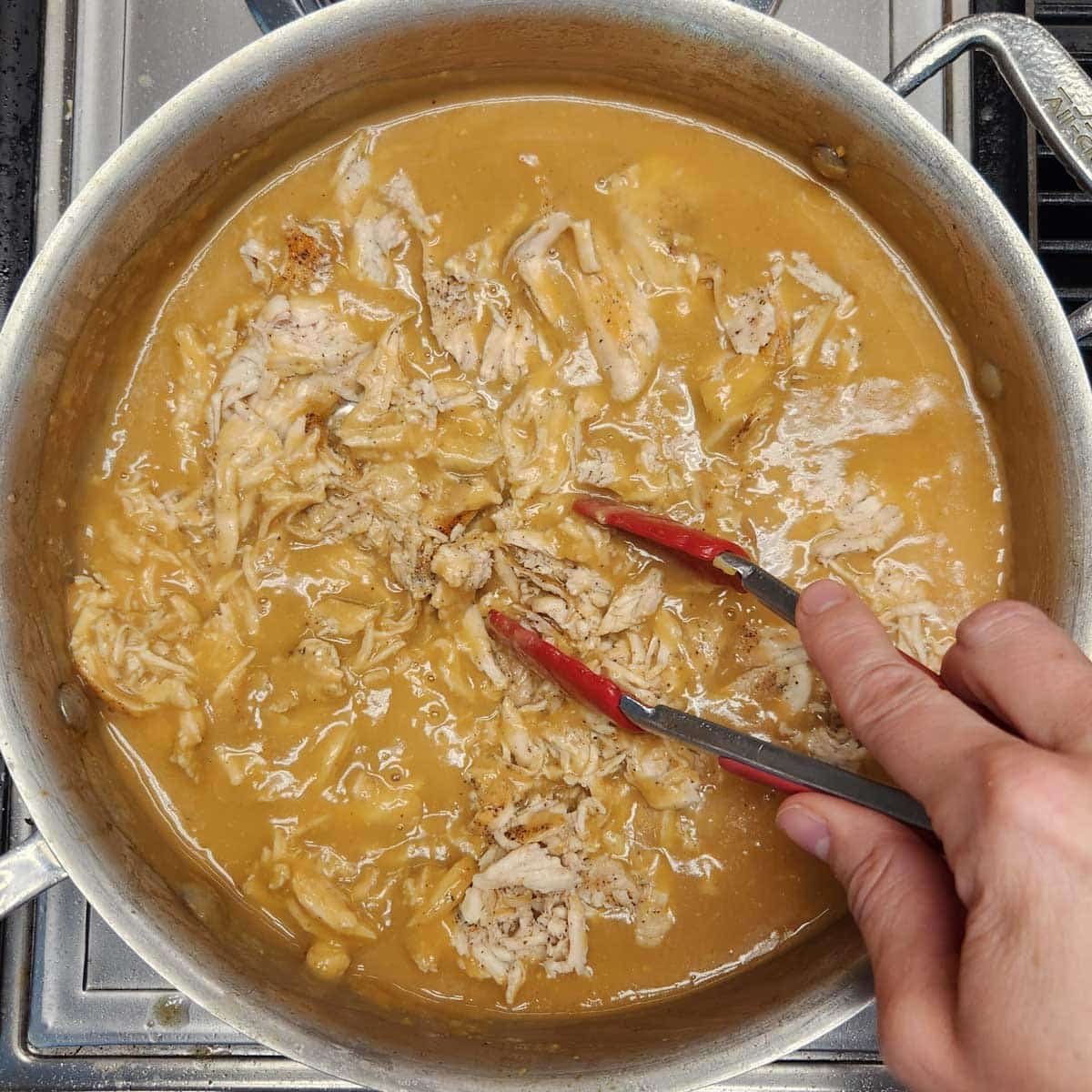 shredded chicken and gravy in a skillet on the stove top