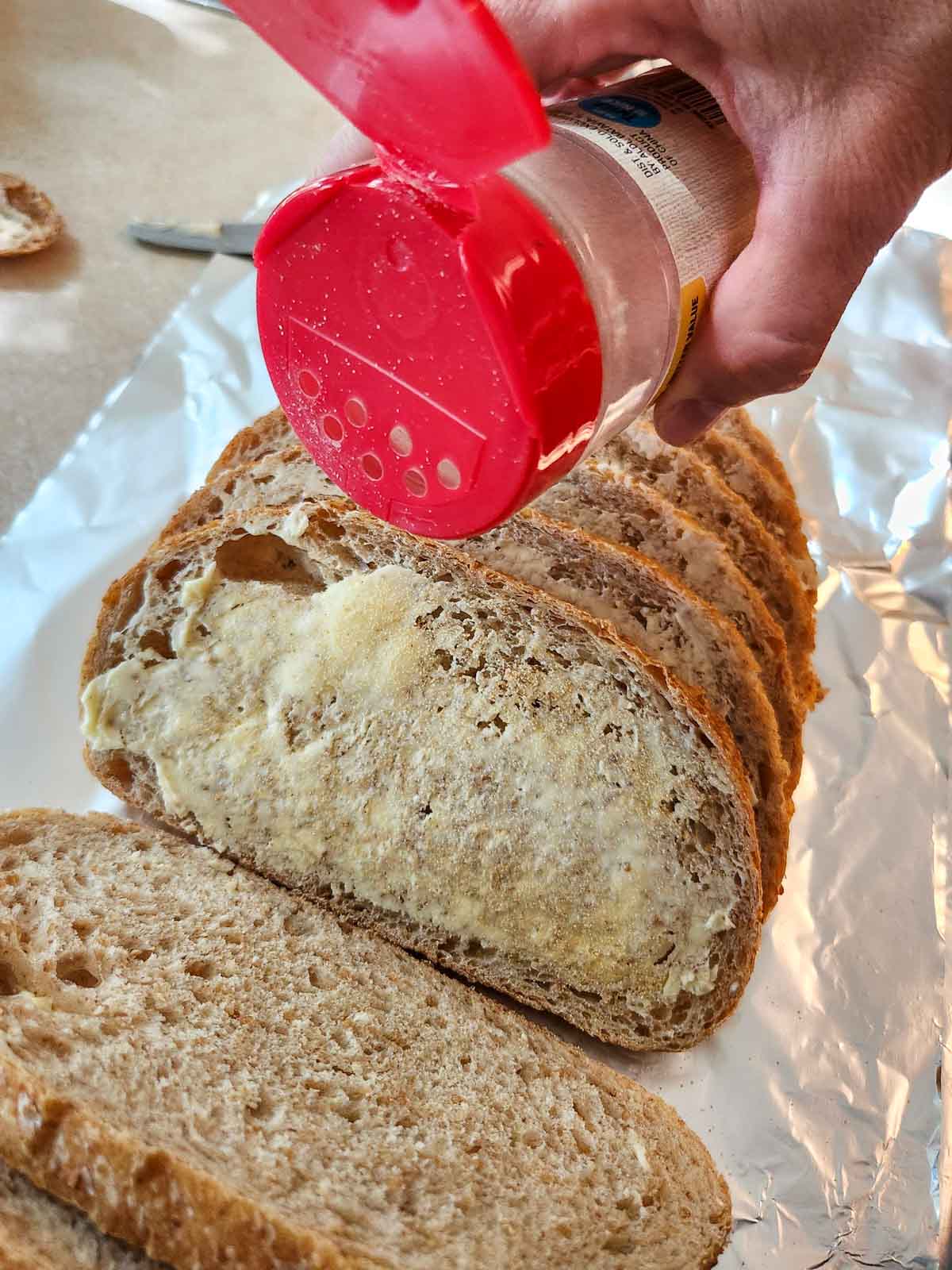 sprinkling garlic powder on bread